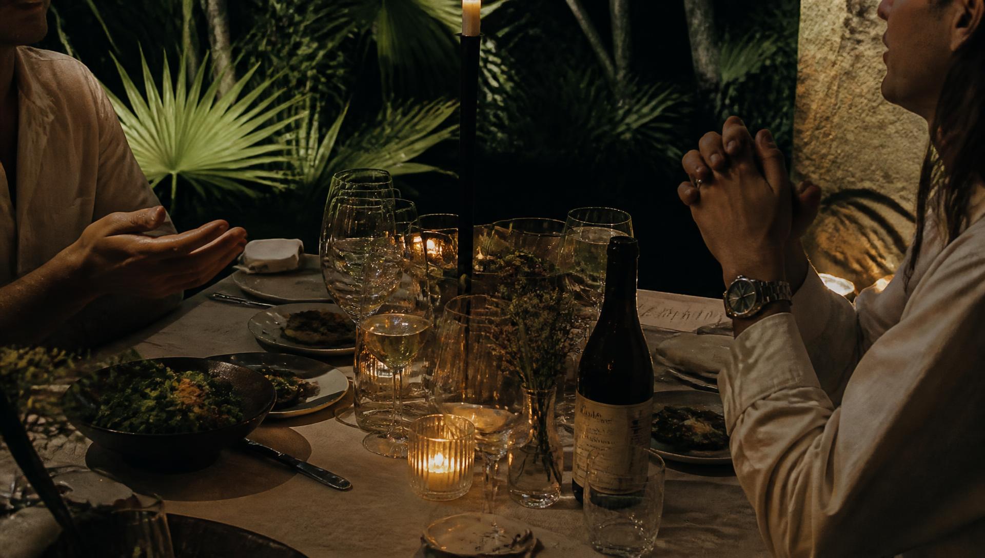 Candlelit dinner table in a garden at dusk